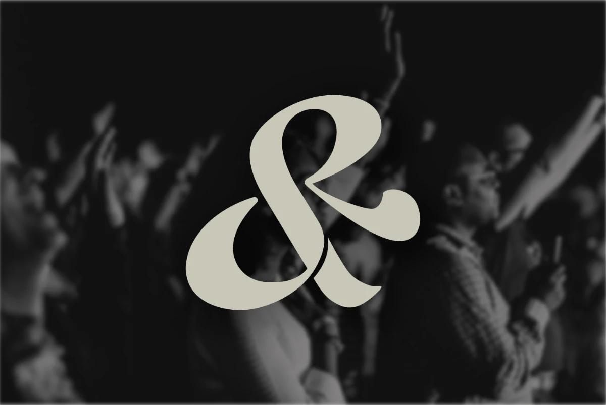 Seek & Remain ampersand mark over a worship crowd